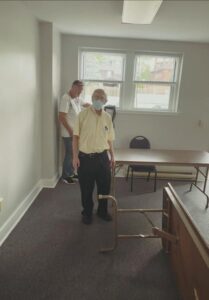 Two club members pause while unfolding tables and chairs and moving them into place.